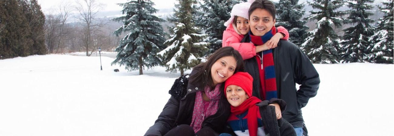17369278 - a beautiful east indian parents play with her children in the snow.